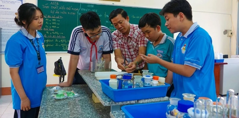 Hoàng Đức Tín (bìa phải) giới thiệu sản phẩm viên nén nhiên liệu cùng thầy giáo và các bạn