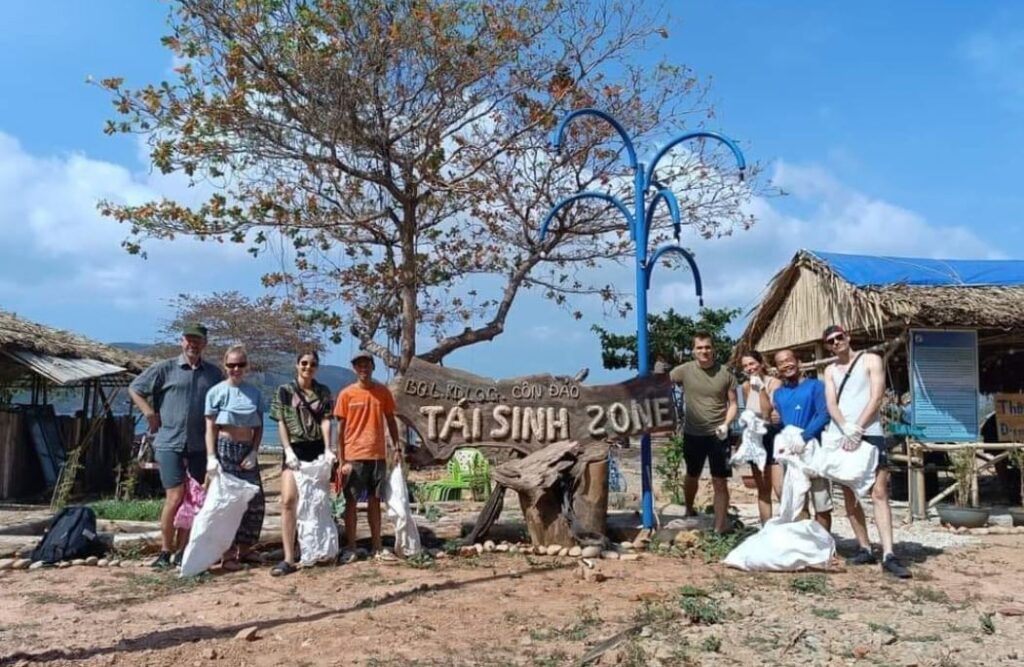 Anh Phương rác (áo xanh, thứ hai từ phải qua) cùng đoàn khách nước ngoài tham gia nhặt rác thải tại khu vực bờ biển gần Tái Sinh Zone. Ảnh: Nguyễn Thanh Thanh.